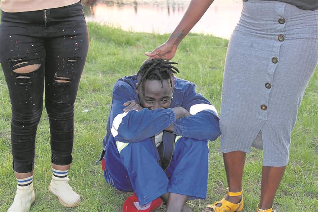 Cousin Naldo Mogomu seen comforted by residents. Photo by Phineas Khoza