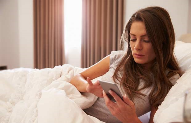 Woman checks phone in bed