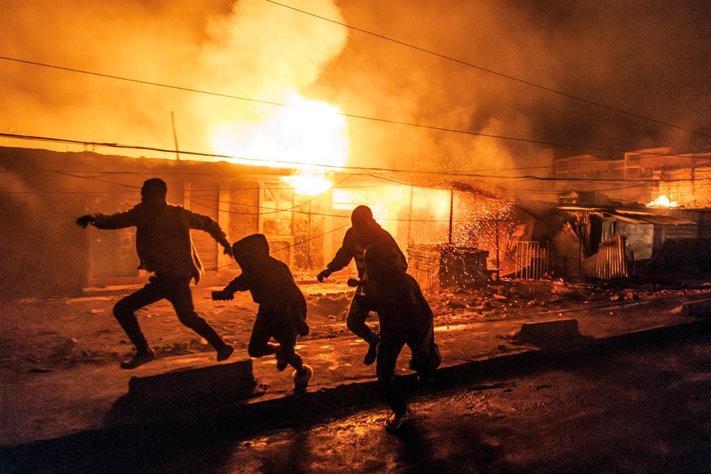 People run for cover following a series of explosions in the Embakasi area of Nairobi on 2 February 2024. At least 30 people have been transferred to different hospitals, according to the Kenya Red Cross, after explosions rocked an industrial and residential area of the Kenyan capital. 