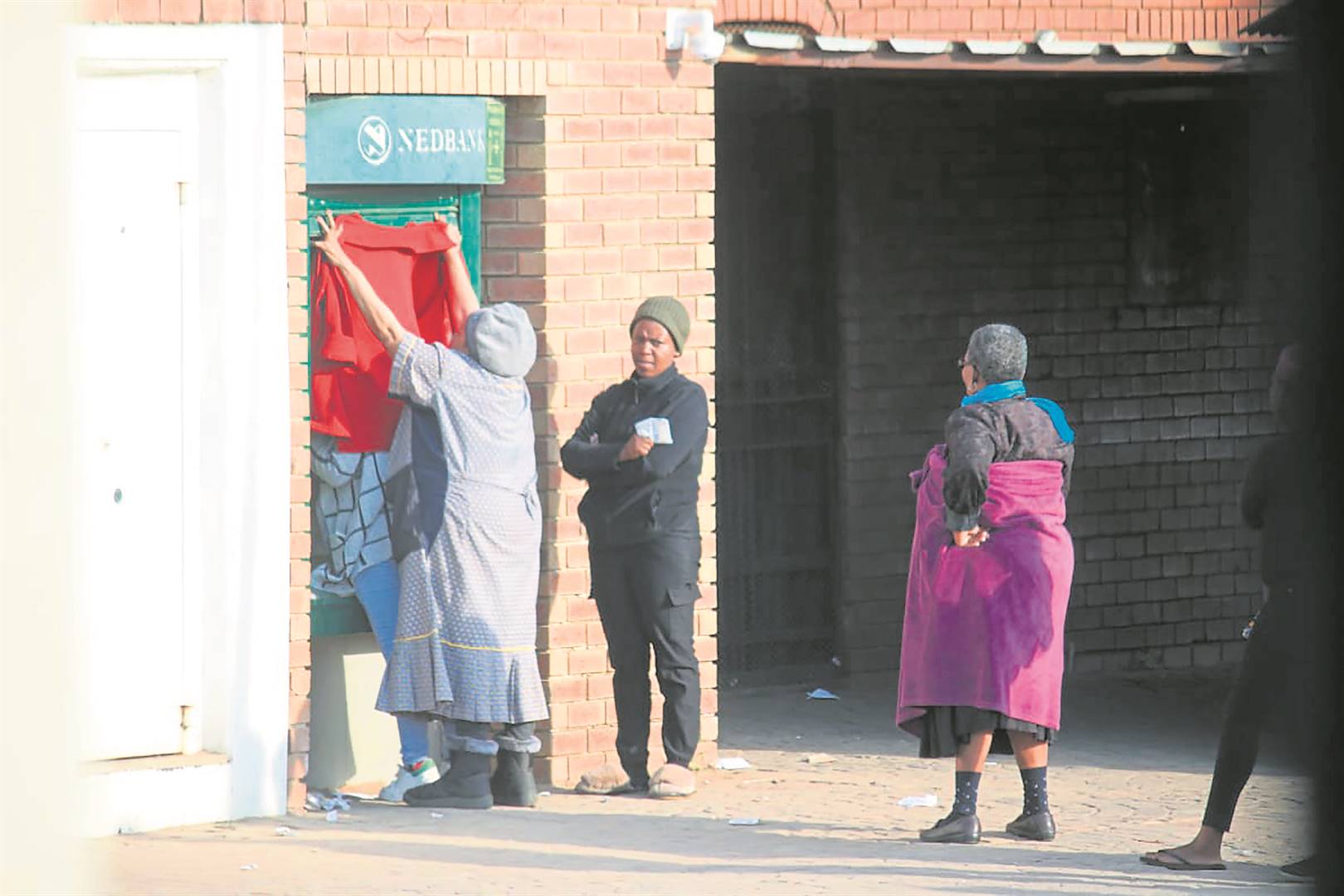 A gogo blocks the ATM while her daughter withdraws money. ­         Photo by Phineas Khoza