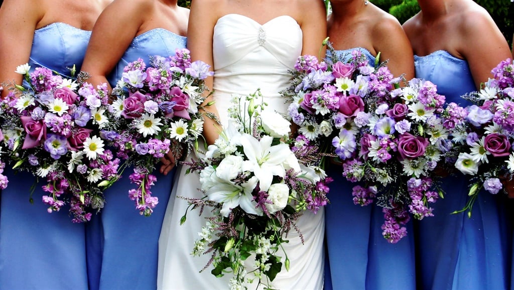 A bride's bouquet surrounded by her bridesmaids holding theirs.  Vibrant colors.