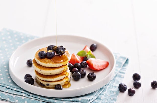 Stack of small pancakes with berries on a plate