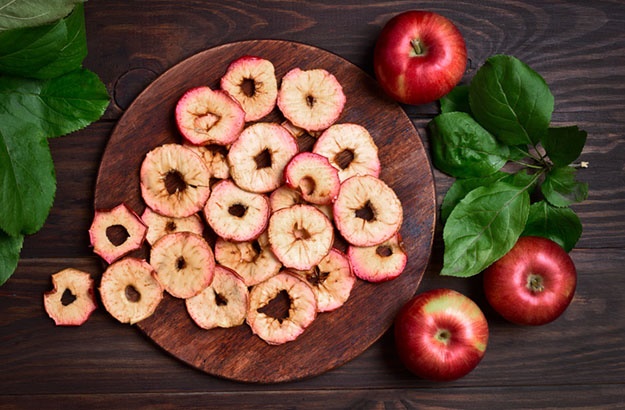 Apples chips on wooden background, top view