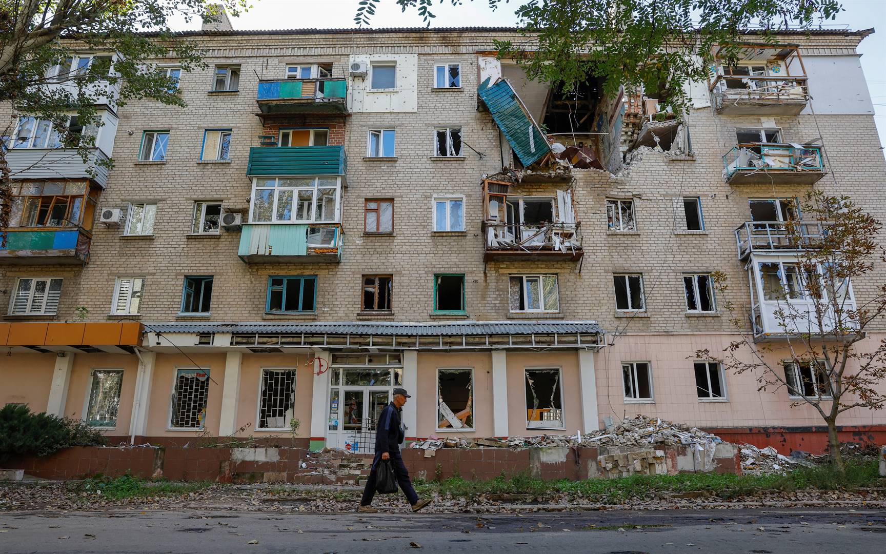 ’n Man stap verby ’n woonstelblok in Lisitsjansk in die Loehansk-gebied op 21 September. Die stad word deur Russiese troepe beheer.  Foto: Reuters