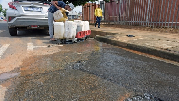 A man collects fresh drinking flowing out of the road in Boshoff street on Monday.