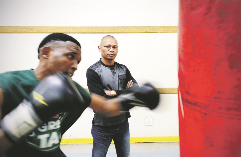Silence Mabuza looks on as one of his boxers hits the bag at his gym in Tsakane, Ekurhuleni. Picture: Leon Sadiki