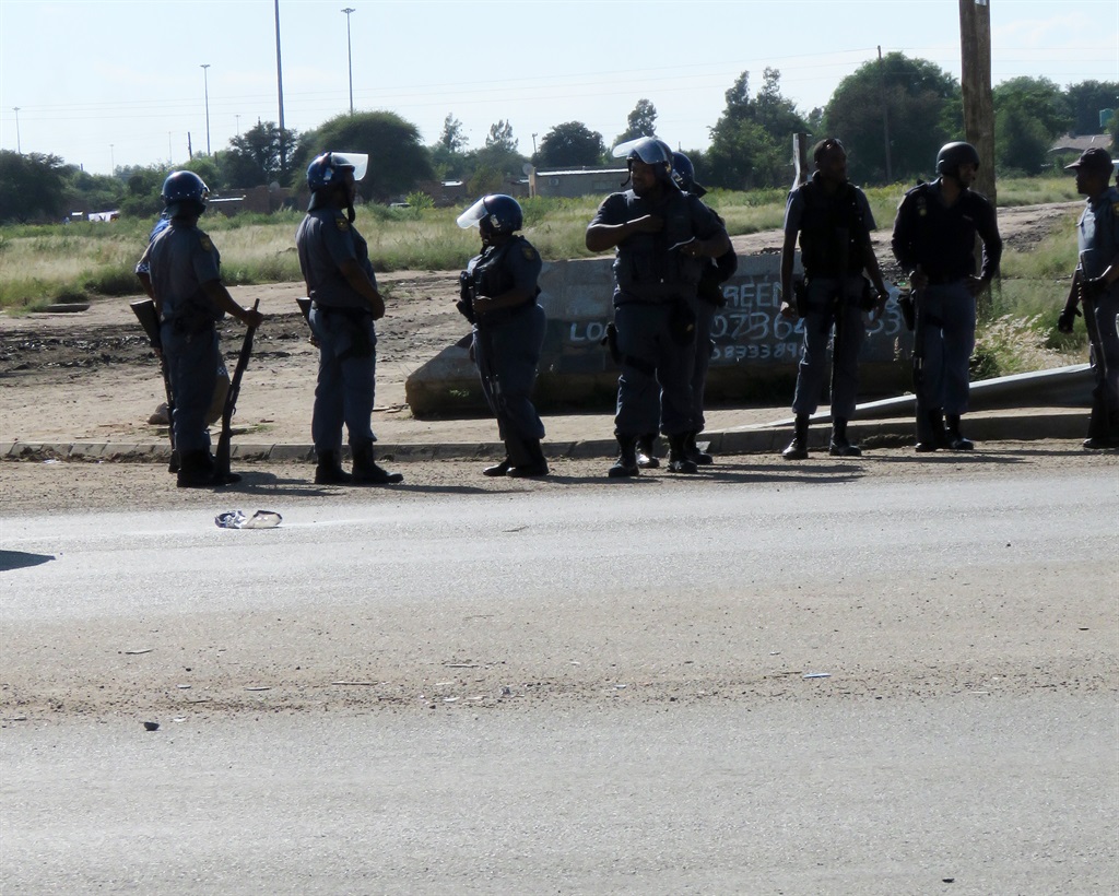 As Cyril Ramaphosa returned early from the UK to try sort out the unrest in the North West, the police had their hands full. A truck was torched, roads were barricaded with burning trees, tyres and stones and officers had to run from one area to the next to rein in the protesters, who want Premier Supra Mahumapelo to resign. Picture: Dulile Sowaga