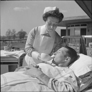 Sanatorium Nursing- Everyday Life at Broomfield Sanatorium, Chelmsford, Essex, England, 1945 A nurse uses a spouted cup to feed a patient in the sunshine of an open air 'ward' of Broomfield Sanatorium, Chelmsford.Soure: Imperial War Musuem, Wikipedia
