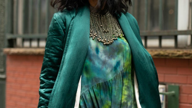 A guest is seen at New York Fashion Week AW19 wearing a sea green coat and a tie dye dress 