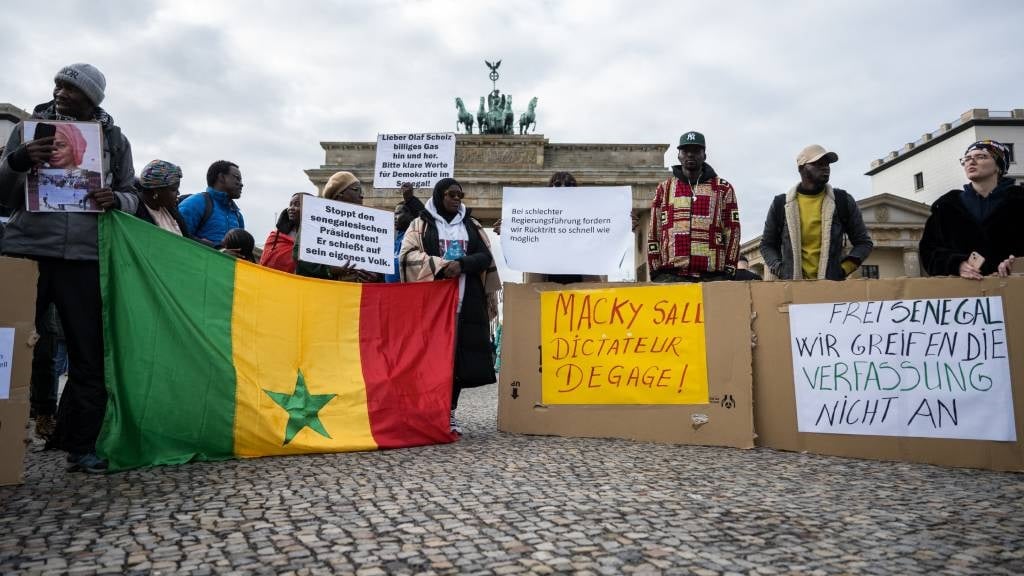 Demonstrators hold banners reading 'Macky Sall dictator: get out!' and 'Free Senegal, we do not touch the Constitution' in a protest against human rights violations in Senegal at the Brandenburg Gate in Berlin.