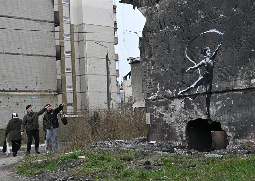 Local residents look at a Banksy-style graffiti on