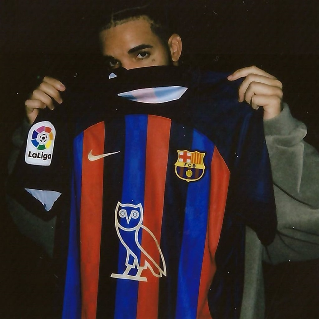Drake holding up Barcelona's home jersey with his 