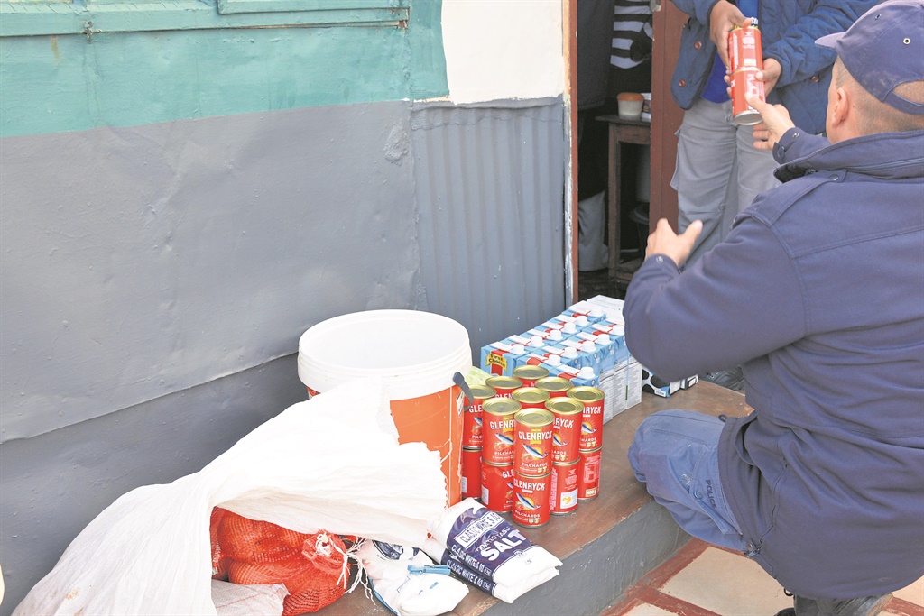 Cops remove canned fish and lots of other food meant for a school feeding scheme from a suspect's house Photo by Morapedi Mashashe 
