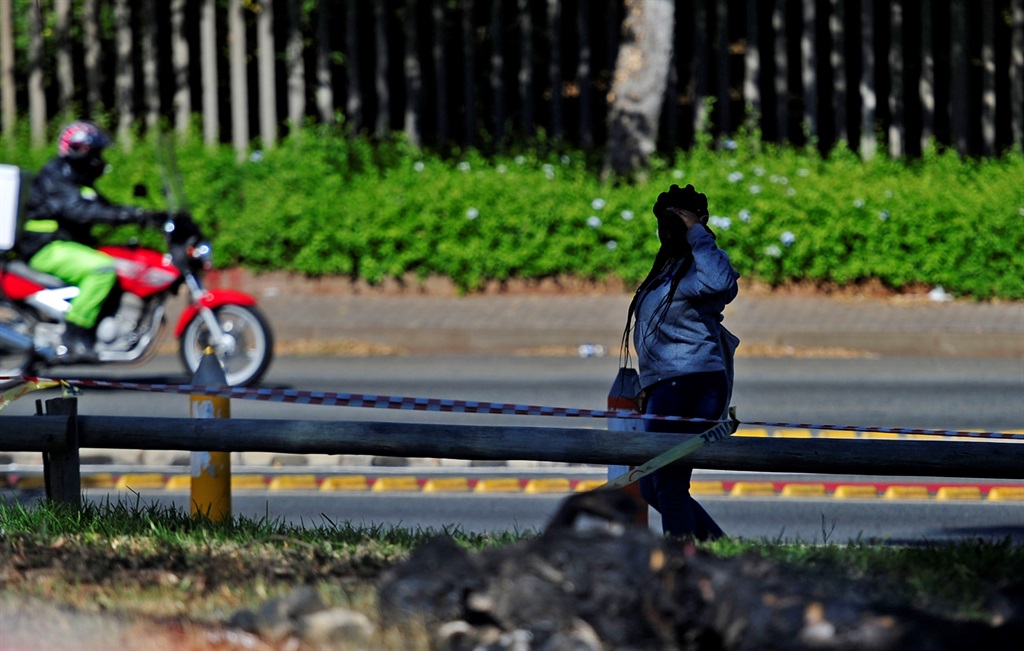 Students walk past the burnt body of man in a park near the University of Johannesburg. Picture: Tebogo Letsie/City Press.