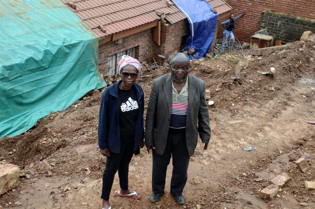  Agnes Shongwe and her dad, Amos Shongwe, standing next to the damaged house. Photo by Raymond Morare