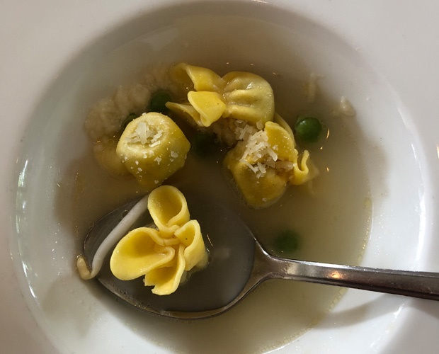 a bowl of fagottini pasta with peas and broth 