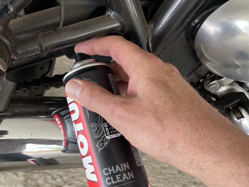 Cleaning the chain on a motorcycle.