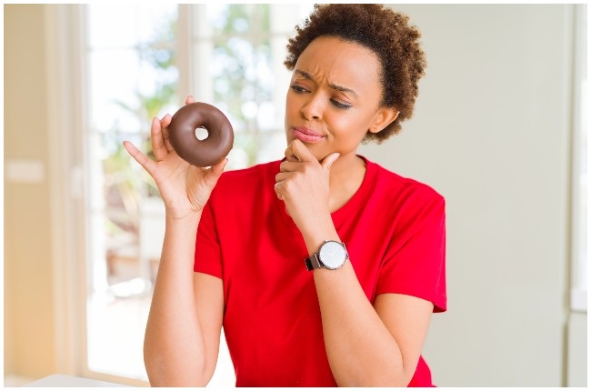 Woman thinking about eating junk food