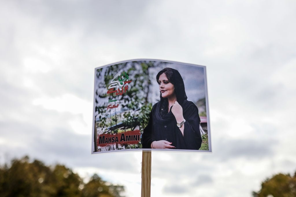 A protester holds a banner with the image of Mahsa Amini.