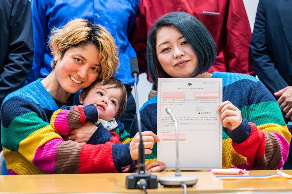 Mamiko Moda (L) and her partner Satoko Nagamura with their son holds a same-sex partnership certificate as they pose for a photograph after a press conference at the Tokyo Metropolitan Government building in Tokyo on November 1, 2022. 