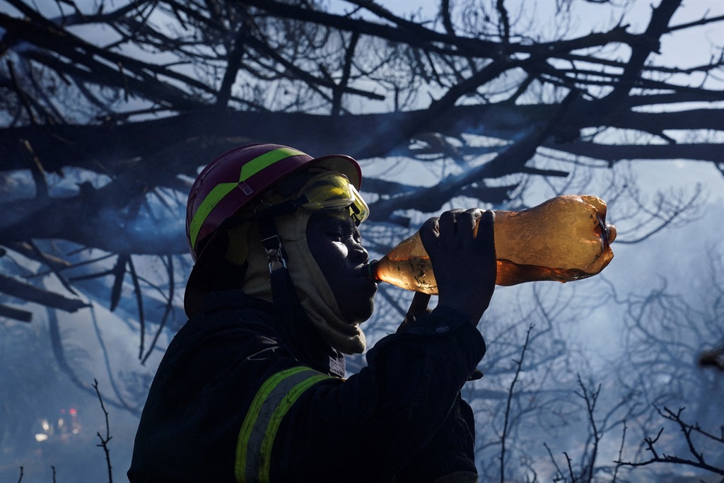 A firewoman drinks water whilst extinguishing a fi