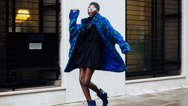 Model walking down the street in blue coat.