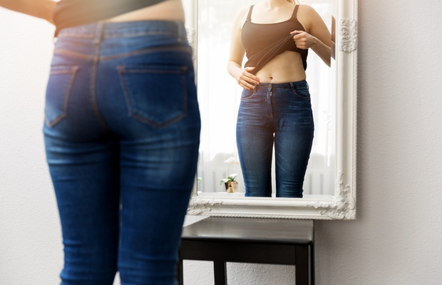 girl looking at her body in mirror 