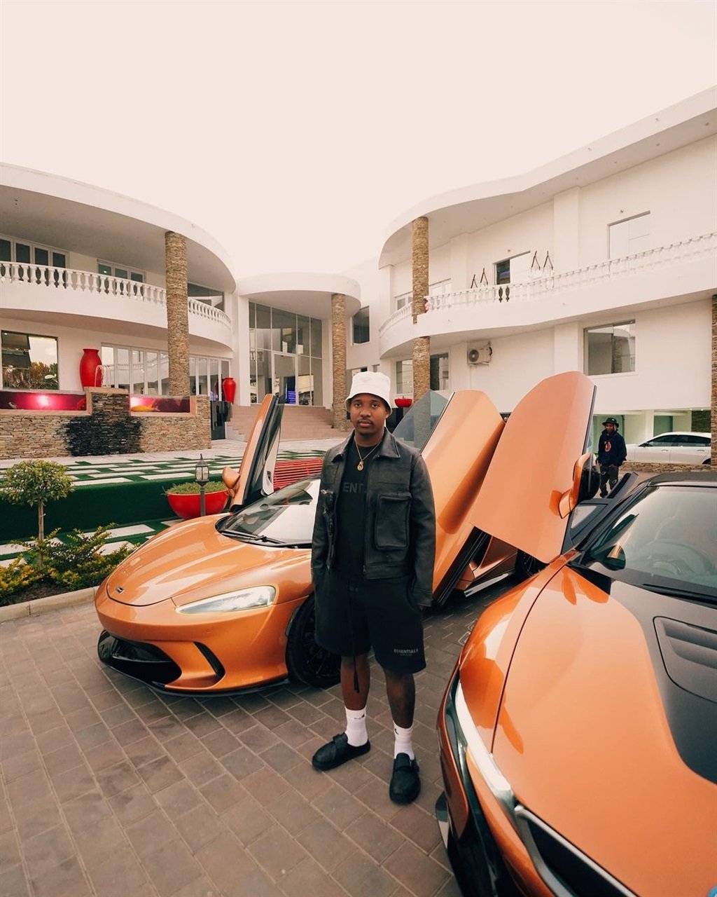 Andile Mpisane alongside his BMW i8 and a McLaren.