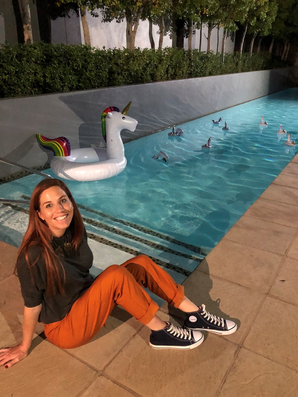 The author poses in front of the hotel's unicorn floatie-filled swimming pool.