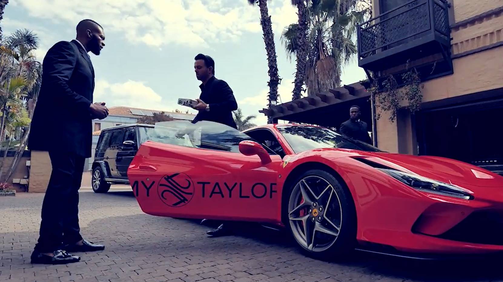 Peet Viljoen parkeer sy rooi Ferrari voor sy huis terwyl twee lyfwagte aan weerskante van die kar staan. Foto: Skermgreep