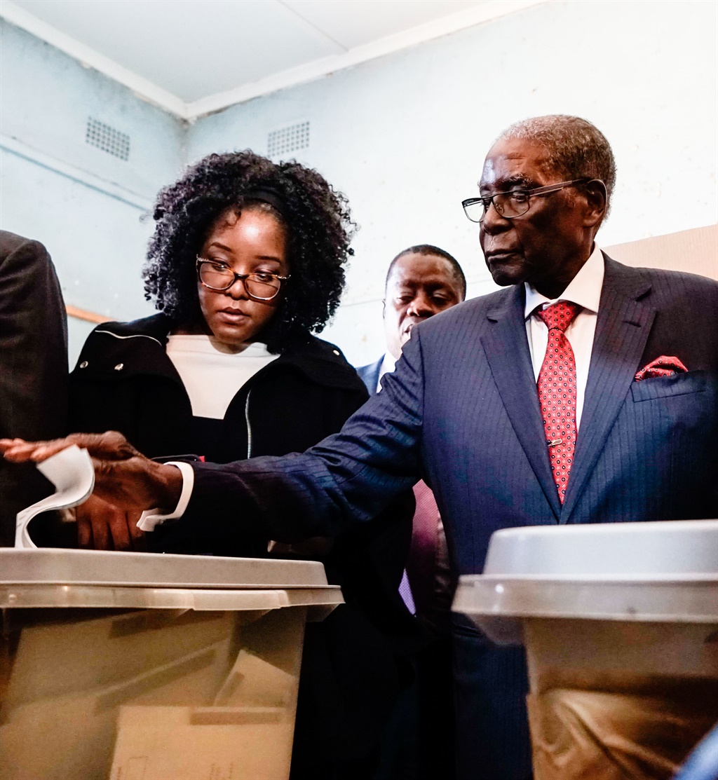 Former Zimbabwean president Robert Mugabe (C) is watched by his daughter Bona (L) and wife Grace as he casts his vote at a polling station located in a primary school in the Highfield district of Harare during the country's general elections. ( File, AFP) 