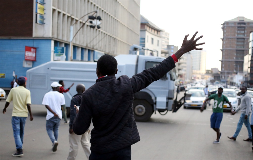 A supporter gestures as a water cannon truck with anti-riot police passes near the MDC headquarters in Harare, Zimbabwe, on Tuesday (July 31 2018). Picture: Siphiwe Sibeko/Reuters