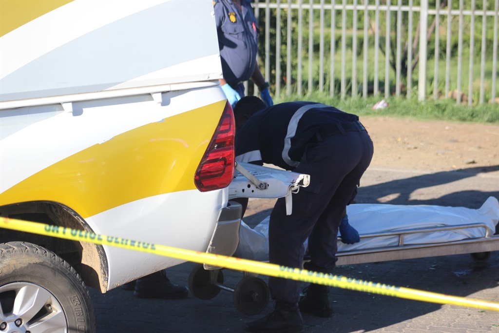 Forensic workers load the body of a man who was stabbed into a mortuary van. Photo by Joseph Mokoaledi