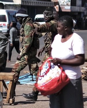 Two Zimbabwean soldiers wearing balaclavas shout orders to street vendors and money changers to leave in the Copacabana market in Harare. (Marco Longari, AFP)
