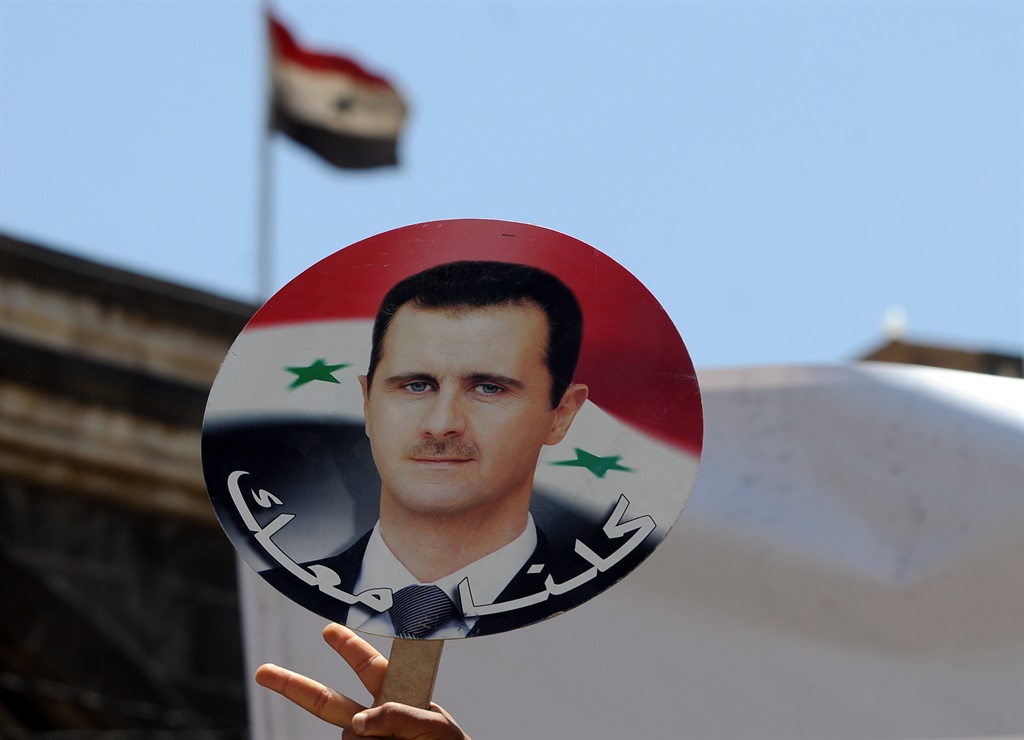 A man holds a photo of Syrian President Bashar al-Assad. (Photo by Mohammed Hamoud/Getty Images)