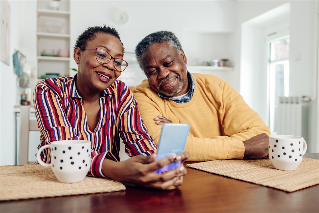 Senior couple using a smartphone at home.