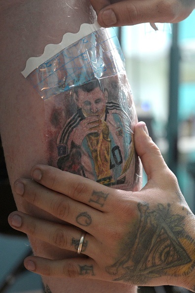 A calf tattoo of Lionel Messi hold the World Cup t