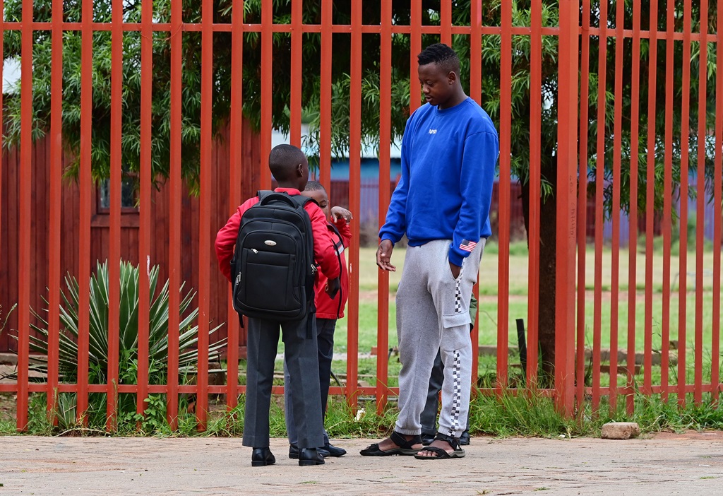 A father says his final goodbyes as his children head off to school. Photo: Trevor Kunene
