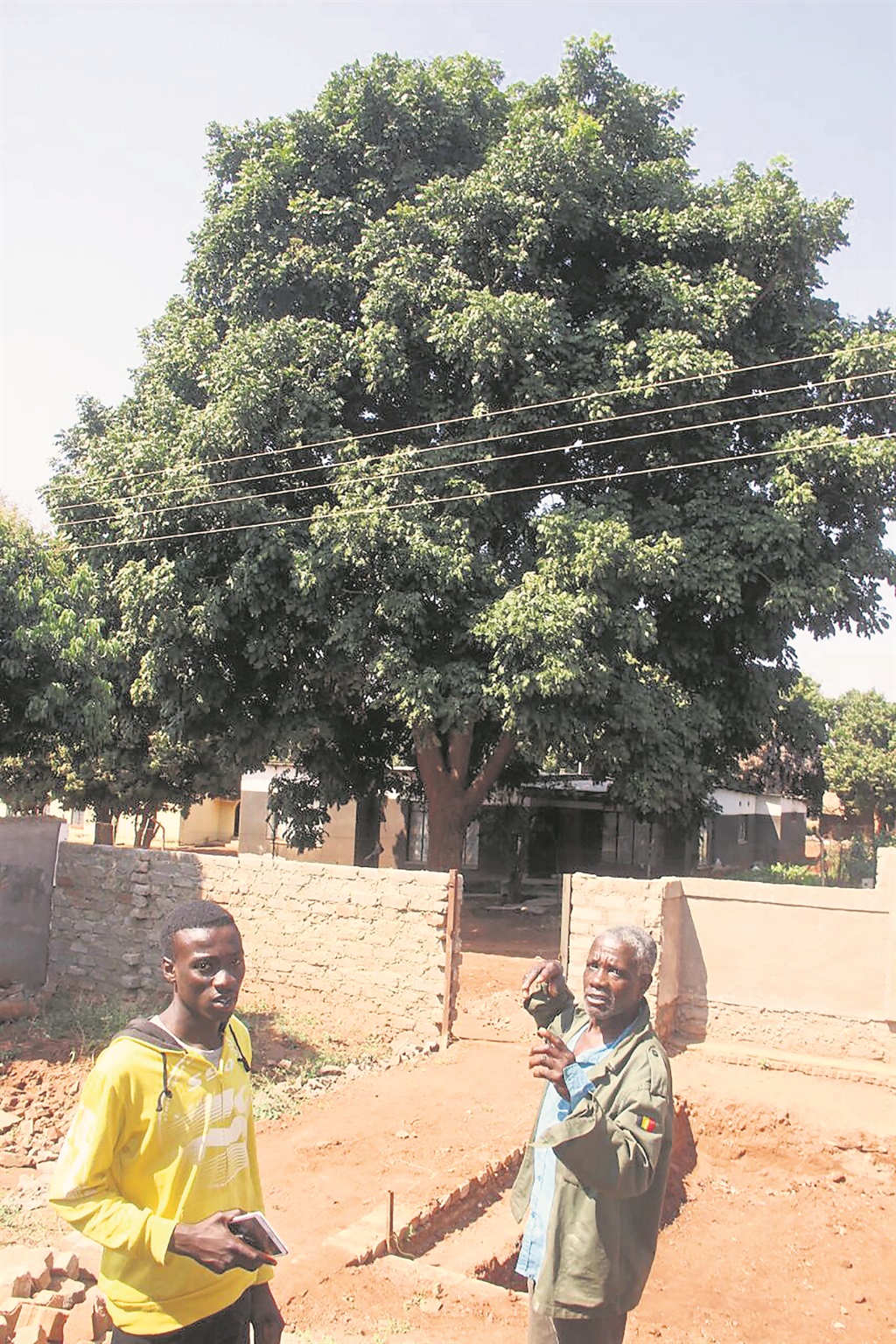 Khodani Nelufule (left) and his Solomon Malema, show the strings stretched over his property.                   Photo by Armando Chikhudo