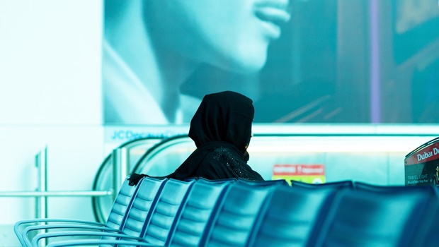 A Muslim woman sitting alone at an airport.