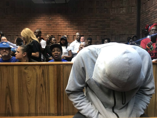 The accused has come back into court, shielding his identity as a number of journalists take images of him as per the court order. (Alex Mitchley, News24)