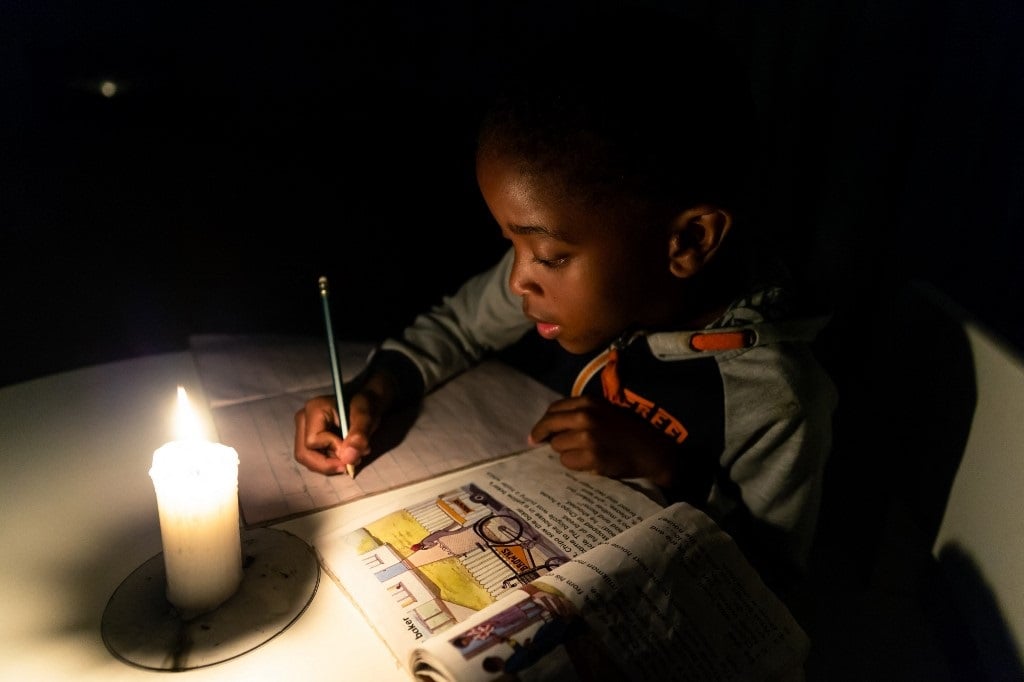 A young Zimbabwean boy does his homework by candlelight in Harare. 