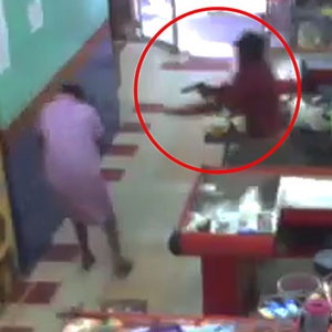 a robber points his firearm at a supermarket employee