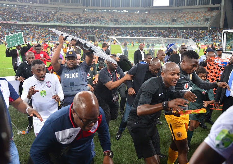 Former Kaizer Chiefs head coach Steve Komphela runs for cover along with Free State Stars' players and match officials after a Nedbank Cup semifinal, which Stars won 2-0, turned violent as Chiefs fans invaded the pitch baying for Komphela's blood shortly after the final whistle at Moses Mabhida Stadium in Durban. 