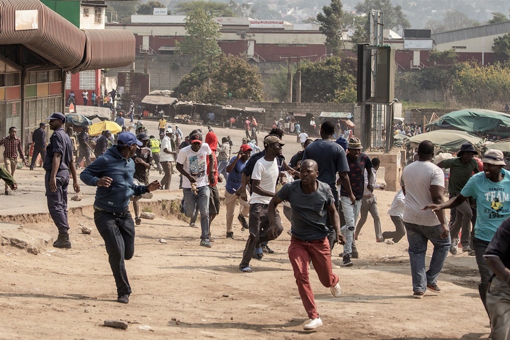 Protesters run for cover as they clash with eSwatini anti-riot police in Manzini. Photo: AFP