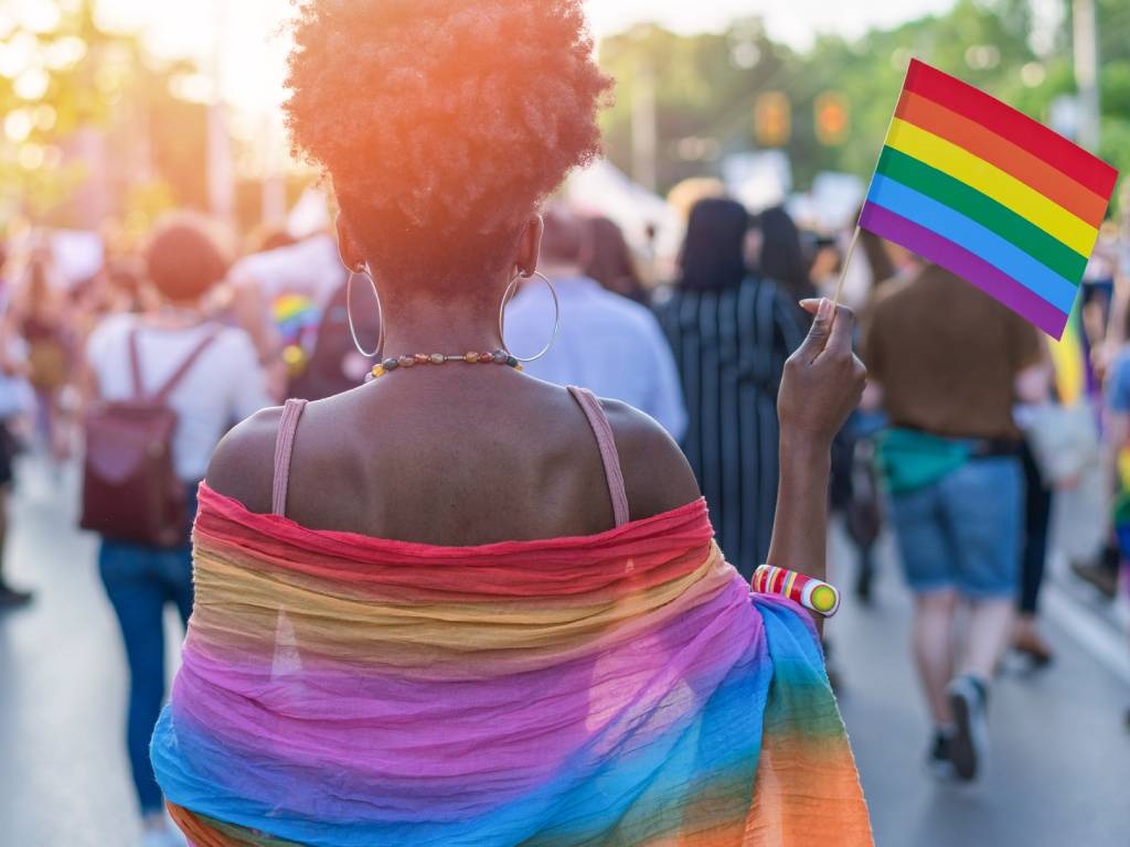 A woman is seen walking at the LGBTQI pride event and waving rainbow flag.