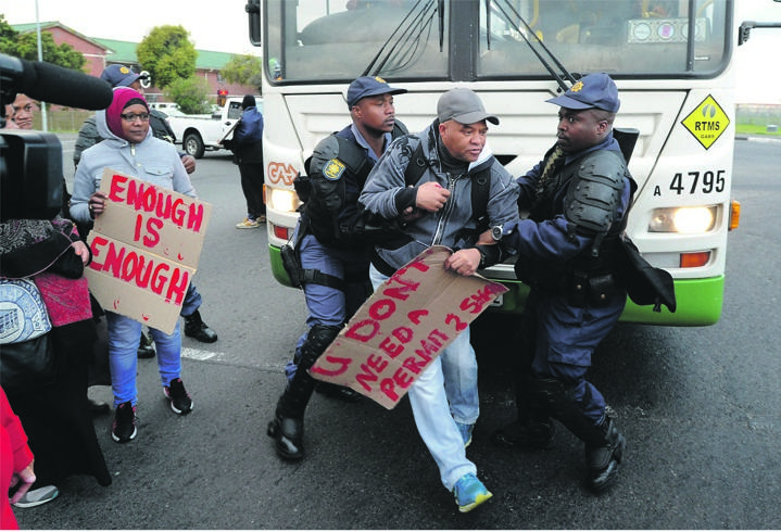 Cops arrest a man during a protest in the Bonteheuwel area yesterday.                                           Photo by Gallo Images / Brenton Geach