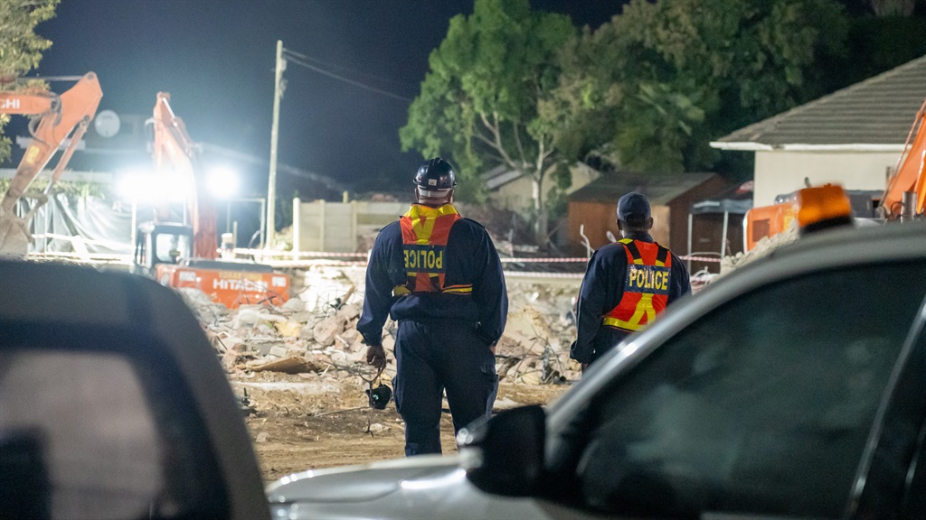 Two Police officers stand near the scene where a building collapsed, killing 24 people. (Alfonso Nqunjana/News24)