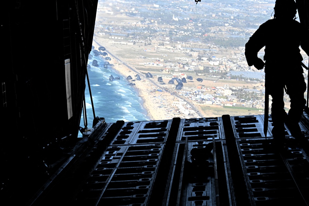 In this image obtained from the US Department of Defense, a US Air Force loadmaster releases humanitarian aid pallets of food and water over Gaza, 2 March 2024. Israel's top ally, the US, said it began air-dropping aid into war-ravaged Gaza on 2 March 2024, as the Hamas-ruled territory's health ministry reported more than a dozen child malnutrition deaths. (Christopher Hubenthal / US Department of Defense / AFP)
