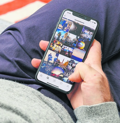 Man holding Barack Obama Instagram photos feed on the new Apple iPhone X 10 Display while seating in couch with Retina Display screen.  